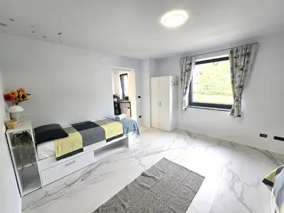 a white bedroom with a bed and a window at Rozna Retreat in Nova Gorica