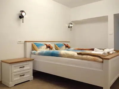 a white bedroom with a bed with a night stand at Apartmaji Pri fijakarju - Apartments 
