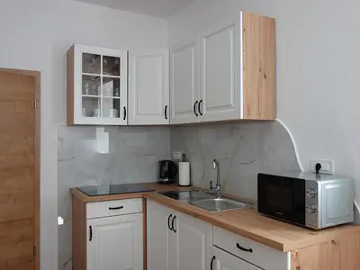 a kitchen with white cabinets and a sink and a microwave at Apartmaji Pri fijakarju - Apartments 