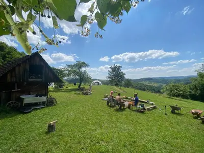 a group of people sitting at a picnic table in a field at Nature-based Retreat by Naj Raste in Senovo
