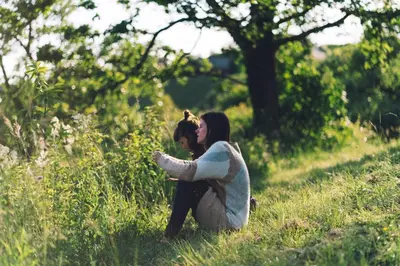 a woman sitting in the grass in a field at Nature-based Retreat by Naj Raste in Senovo