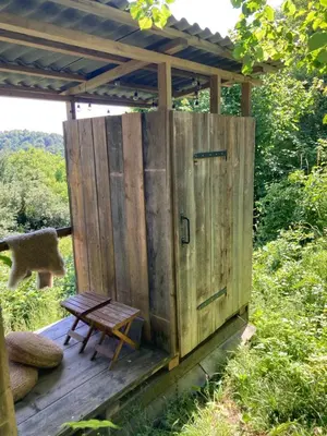 a wooden outhouse with a bench on a deck at Nature-based Retreat by Naj Raste in Senovo
