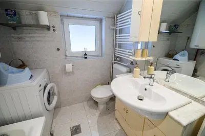 a bathroom with a sink and a toilet and a window at Apartment Marni w/ Parking | Kranjska Gora in Kranjska Gora