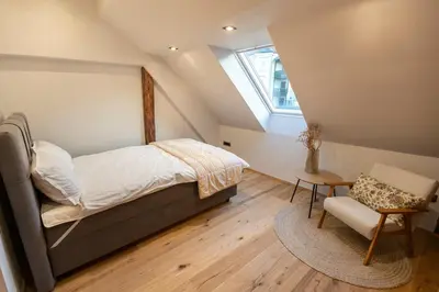 a bedroom with a bed and a chair and a window at Gris Apartment in Gornja Radgona