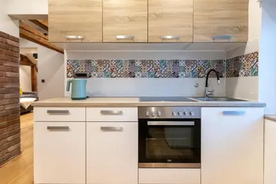 a kitchen with white cabinets and a stove top oven at Gris Apartment in Gornja Radgona