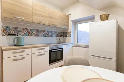 a kitchen with white cabinets and a white refrigerator at Gris Apartment in Gornja Radgona