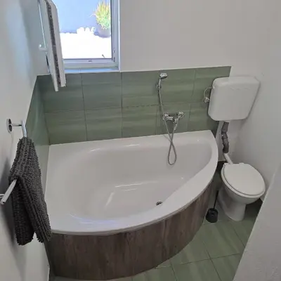 a bathroom with a bath tub and a toilet at Apartma Kolpa Krasinec in Gradac