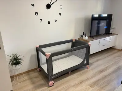 a crib in a room with a clock on the wall at Maribella Apartment in Maribor