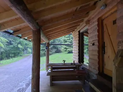 a porch of a log cabin with a bench and a window at Loghouse cabin in the Kočevje forest in Kočevje