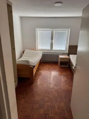a small room with a bed and two windows at Lipovska Oaza