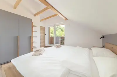 a white bedroom with a large bed and a window at Brlog 2 in Zgornje Gorje