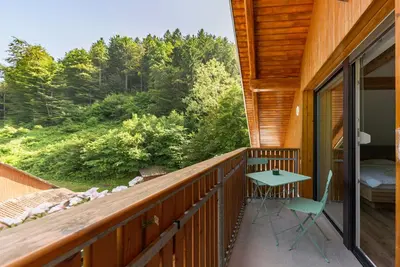 a balcony with a bed and a desk and a table at Brlog 2 in Zgornje Gorje