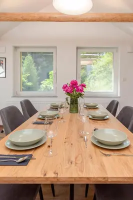 a wooden table with plates and glasses and flowers on it at Brlog 2 in Zgornje Gorje