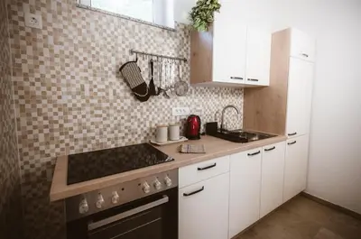 a kitchen with white cabinets and a stove top oven at Chonky Cat in Moravske Toplice