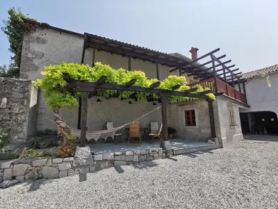 a pergola with a table and chairs in front of a house at Domus Carstica in Sežana