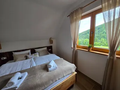 a bedroom with a bed and a large window at Savinjski raj in Mozirje