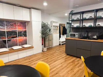 a kitchen with white cabinets and yellow chairs and tables at Central Hostel Lesce-Bled in Lesce