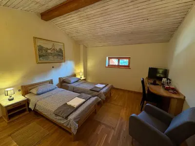 a bedroom with two beds and a table and a couch at Omnia rooms in Sežana