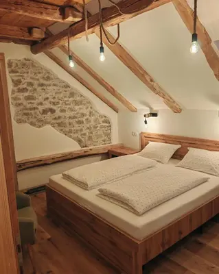 a bed in a room with a stone wall at Hiša Šturm in Tolmin