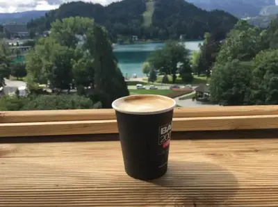 a cup of coffee sitting on a table in front of a window at Lake and Castle view apartment in Bled