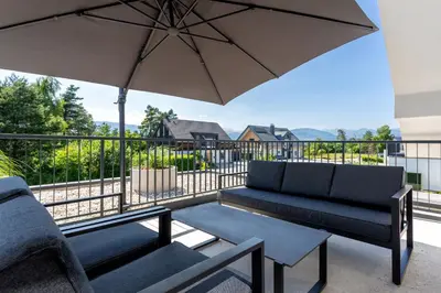 a patio with a couch and an umbrella at Sunny Green Escape - Apartment with Terrace in Lesce