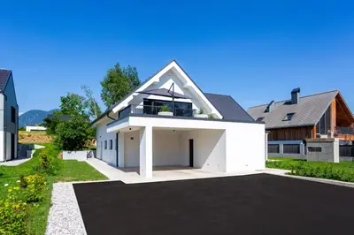 a large white house with a garage at Sunny Green Escape - Apartment with Terrace in Lesce