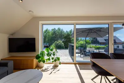 a living room with a tv and a table and chairs at Sunny Green Escape - Apartment with Terrace in Lesce