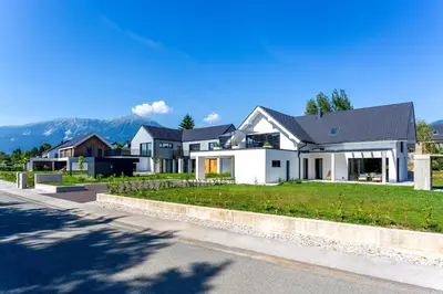 a row of houses with mountains in the background at Sunny Green Escape - Apartment with Terrace in Lesce