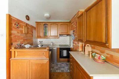 a kitchen with wooden cabinets and a brick wall at Happy Brook Bled in Bled