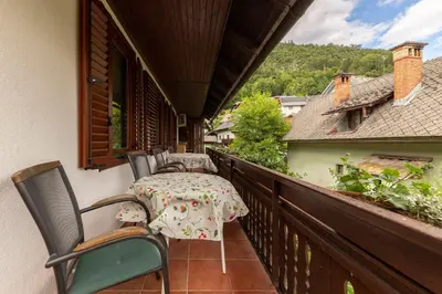 a patio with a table and chairs on a balcony at Happy Brook Bled in Bled