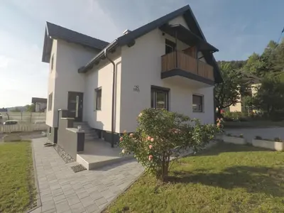 a white house with a balcony and a tree at MaxLux Apartments in Slovenj Gradec