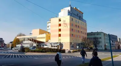 people crossing a street in front of a building at hotel Diana in Murska Sobota