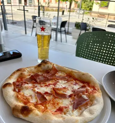 a pizza sitting on a table with a glass of beer at hotel Diana in Murska Sobota