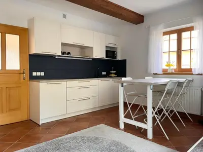 a kitchen with white cabinets and a table with stools at The Little Fern Apartment in Rovte