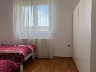a bedroom with a window and a bed and a wooden floor at Apartma DaPDa in Spodnje Škofije