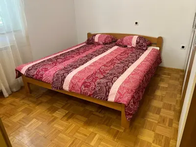 a bed in a bedroom with a wooden floor at Apartma DaPDa in Spodnje Škofije