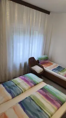 a room with two beds and a chair and a window at Sobe Godina in Materija