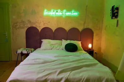 a bedroom with a bed with a neon sign on the wall at Alma ART B&B in Dobrovo