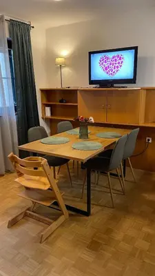 a dining room table with chairs and a television with a heart on the screen at Terme Čatež apartma Solist