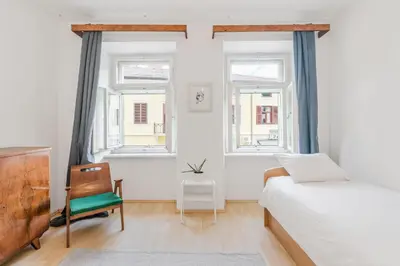 a bedroom with a bed and a chair and windows at Hiša Vuga in Tolmin