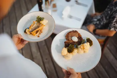 a person holding two plates of food on a table at Glamping Bizjak in Preddvor