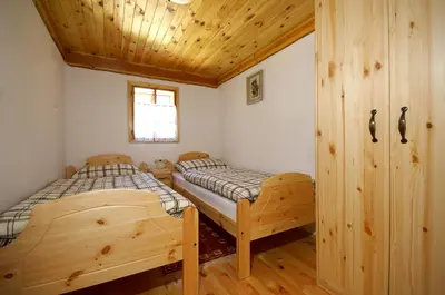 two beds in a room with a wooden ceiling at Turistična kmetija Povh in Prevalje