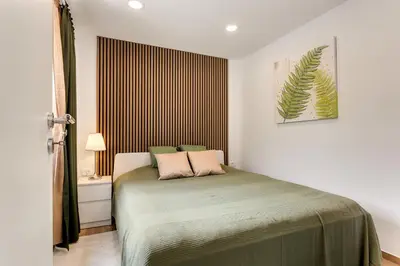 a bedroom with a bed with a green blanket at Mirola homes - rent in nature in Zagorje ob Savi