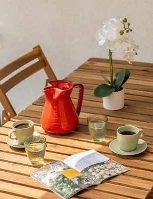 a wooden table with a red pitcher and cups and flowers at Mirola homes - rent in nature in Zagorje ob Savi