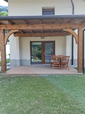 a wooden pergola with two benches on a patio at Apartments Serafina in Tolmin