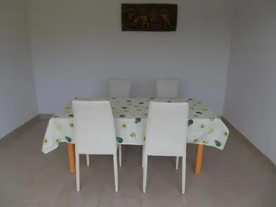 a dining room table with three white chairs around it at Apartma Prima in Podbočje