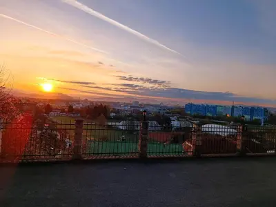 a sunset behind a fence in front of a city at Penthouse Villa Ljubljana in Šentvid