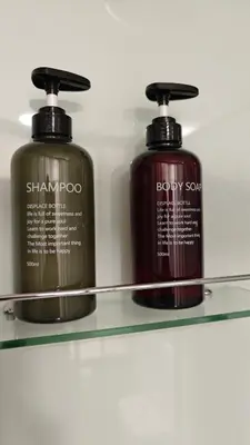 two bottles of shampoo and baby soap on a glass shelf at Relax Tiny House Ljubljana in Ljubljana