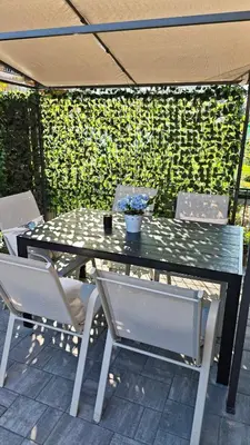 a table and chairs on a patio with a green wall at Relax Tiny House Ljubljana in Ljubljana