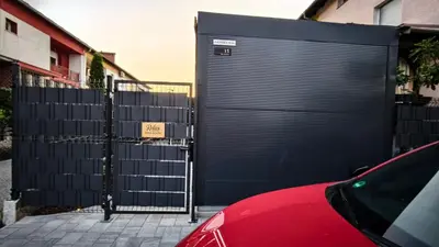 a garage door with a red car parked next to a fence at Relax Tiny House Ljubljana in Ljubljana